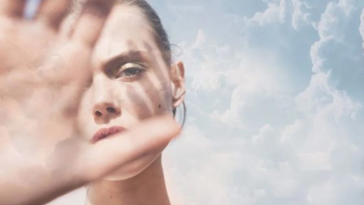 A person reaching out against a serene sky filled with fluffy clouds, conveying a sense of openness and connection.