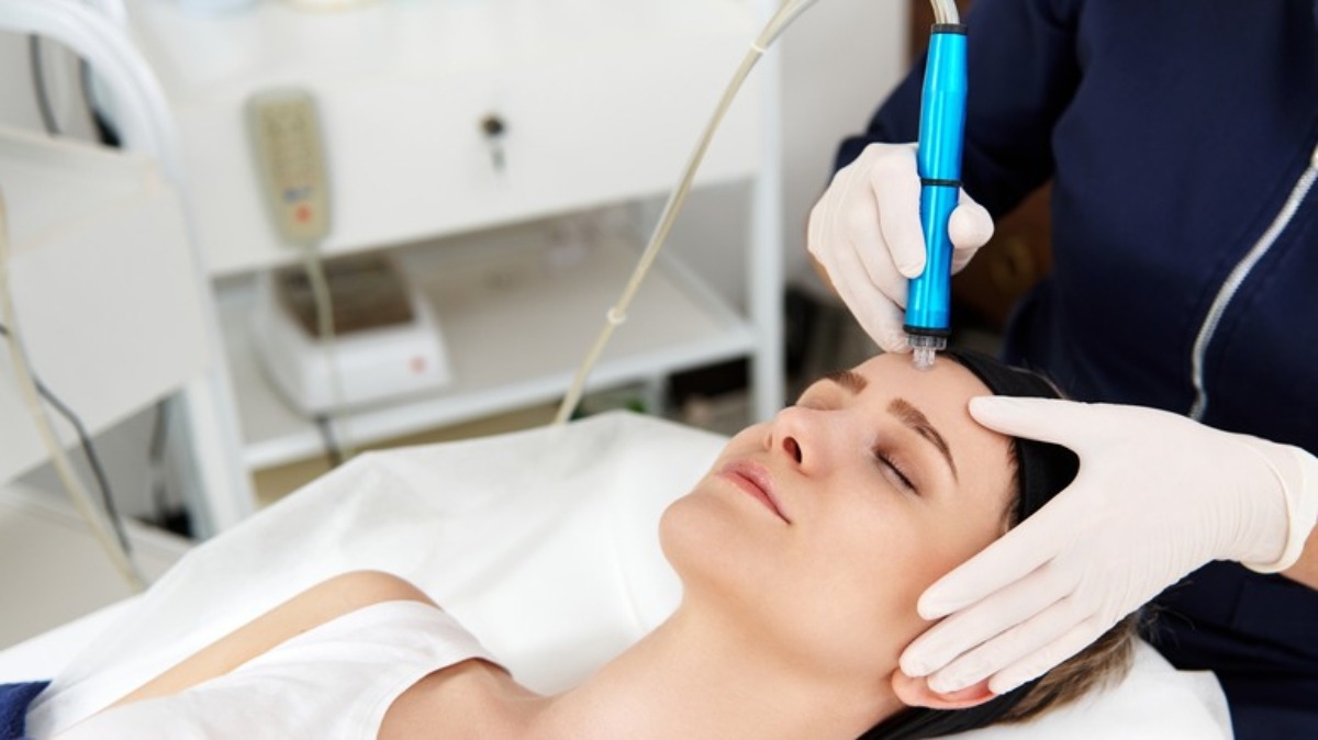 A healthcare professional performs a treatment with a blue device on a patient's neck, showcasing a clinical setting.