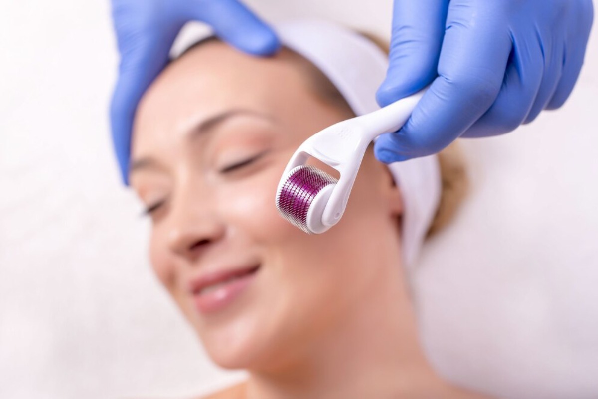 A close-up of a person receiving a skincare treatment, hands gloved in blue, applying a cotton pad to the skin.