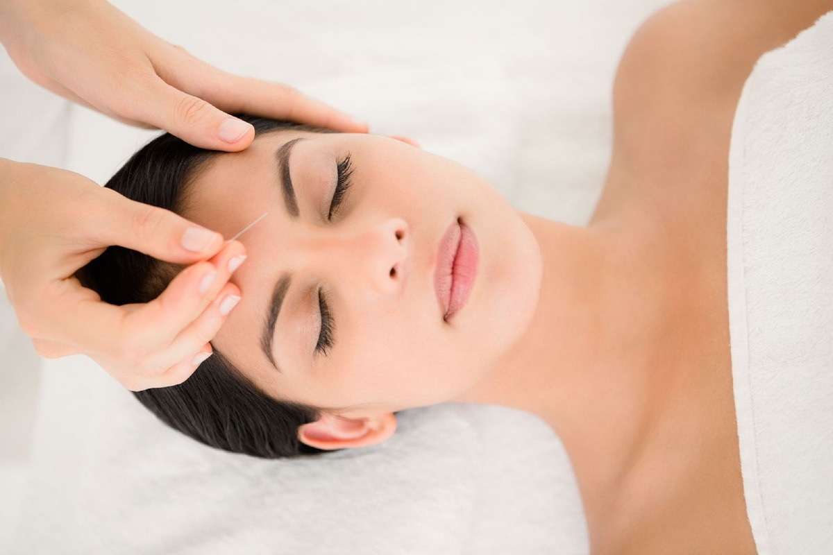 A person receiving a relaxing hair massage, lying on a towel-covered table, with hands gently working through their hair.