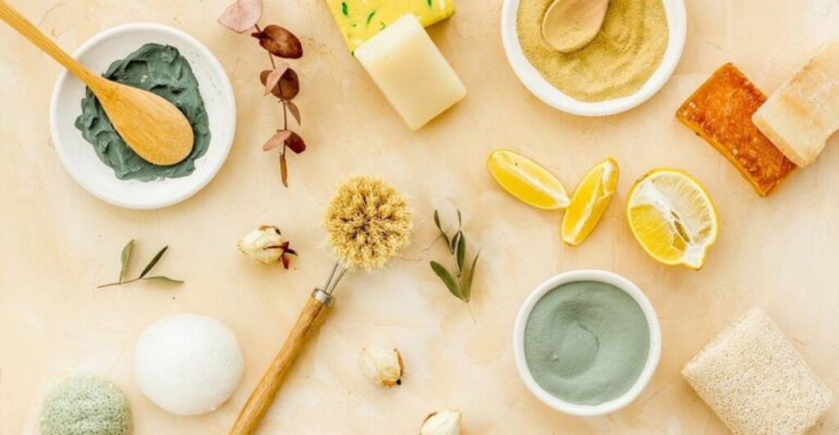 A flat lay of natural skincare products: clay masks, bars of soap, lemon slices, and dried flowers on a textured background.